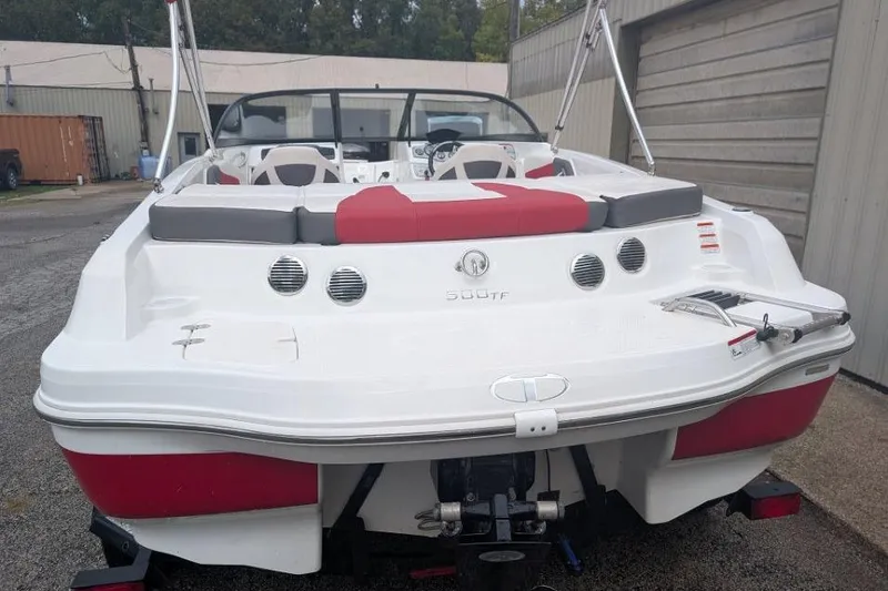 Slide: The Image of 2019 Tahoe 500 TF boat, white and red, parked outdoors near a building. - 2