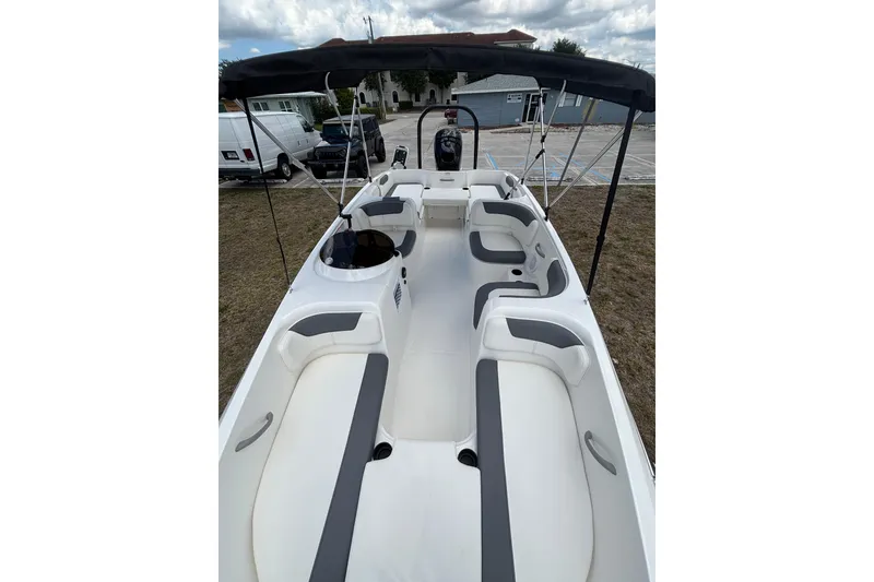Slide: The Image of 2026 Bayliner Element E18 boat interior with spacious seating and canopy, parked outdoors. - 10