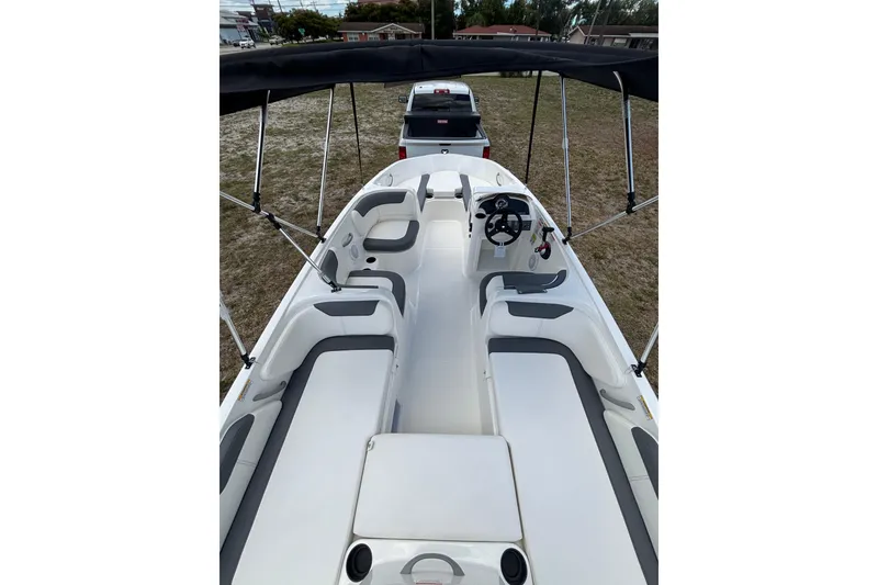 Slide: The Image of 2026 Bayliner Element E18 boat interior with seating and steering wheel, parked on grass. - 12