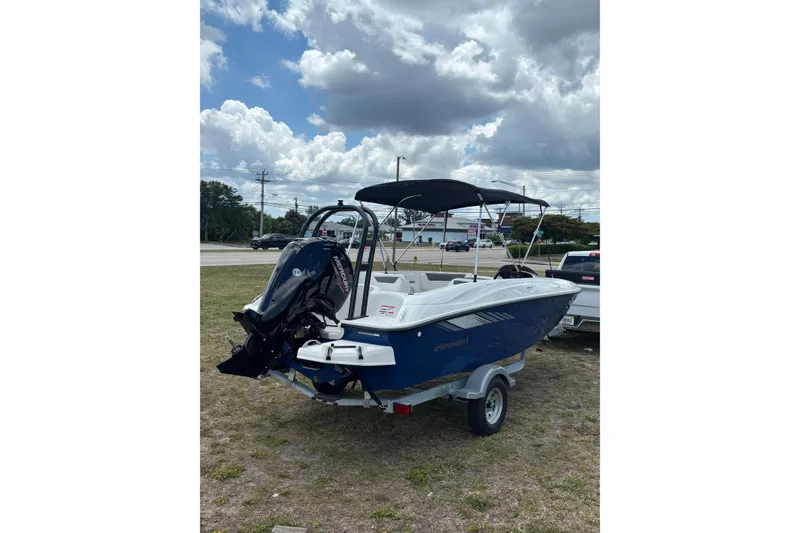 Slide: The Image of 2026 Bayliner Element E18 boat with outboard motor on a trailer, under cloudy sky. - 16