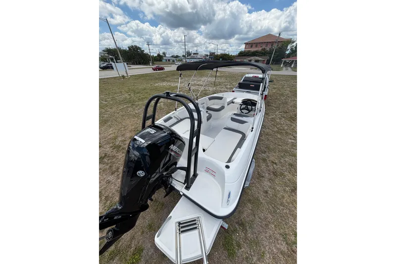 Slide: The Image of 2026 Bayliner Element E18 boat with Mercury engine, parked on grass under cloudy sky. - 6