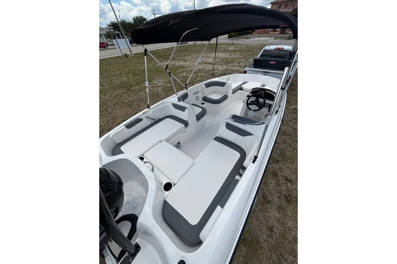 Slide: The Image of 2026 Bayliner Element E18 boat interior with seating and canopy, parked on grass. - 7