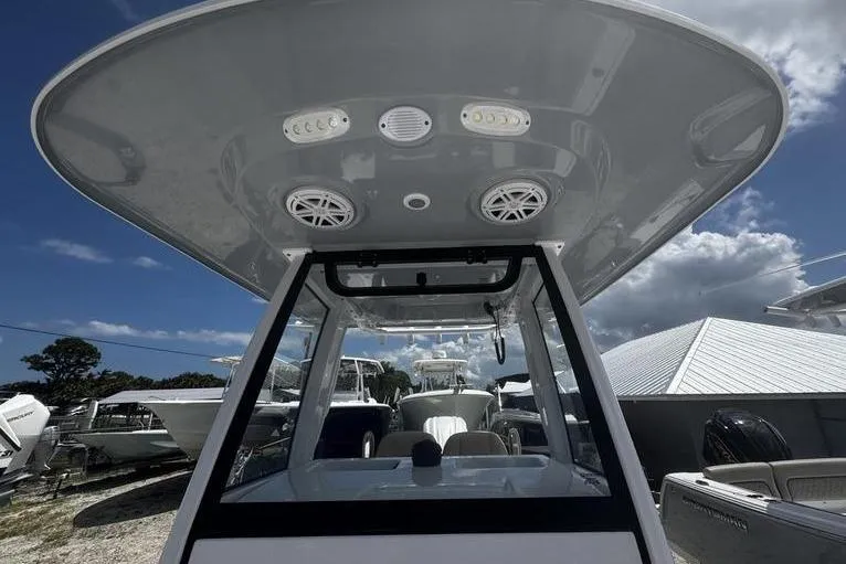 Slide: The Image of 2026 Sportsman Masters 247 Bay Boat with T-top and speakers, docked under a blue sky. - 18