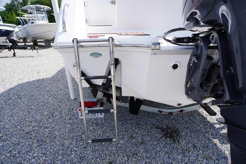 Slide: The Image of 2023 Tidewater 232 CC Adventure boat with ladder and outboard motor on gravel. - 10