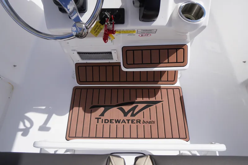 Slide: The Image of 2023 Tidewater 232 CC Adventure boat cockpit with branded floor mats and steering wheel. - 17