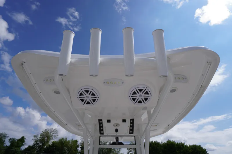 Slide: The Image of 2023 Tidewater 232 CC Adventure boat top view with rod holders and speakers against blue sky. - 18
