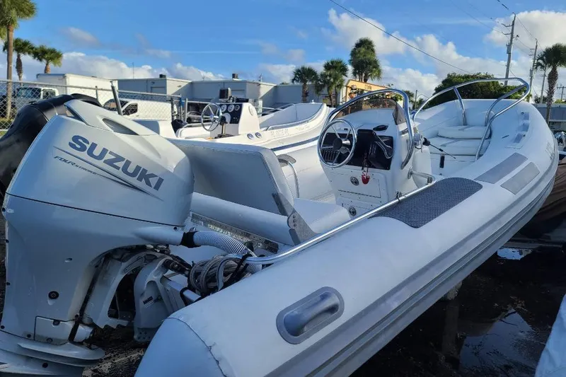 The Image of 2009 Nautica 15 DL inflatable boat with Suzuki outboard motor, parked outdoors. - 0