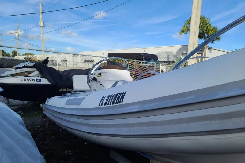 Slide: The Image of 2009 Nautica 15 DL boat parked outdoors near a fence, under a clear blue sky. - 2