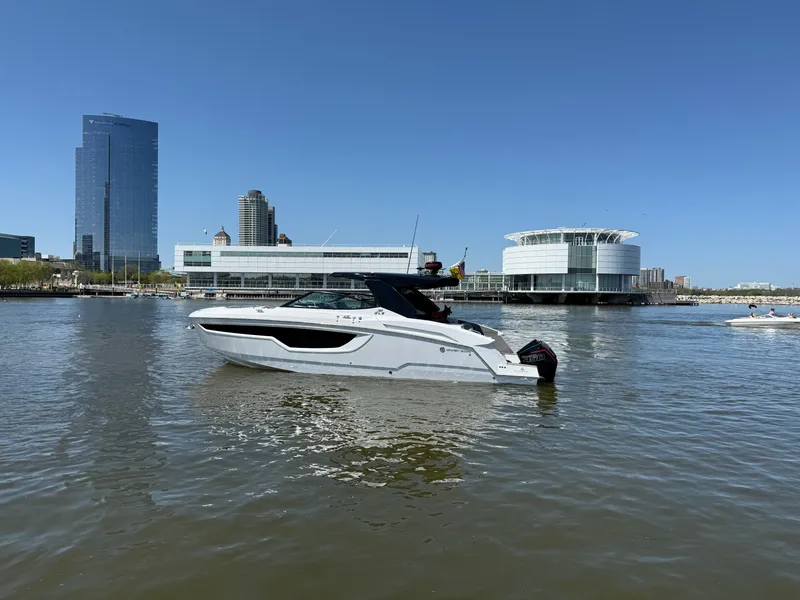 Slide: The Image of 2021 Cruisers Yachts 38 GLS on calm water with modern skyline backdrop. - 12