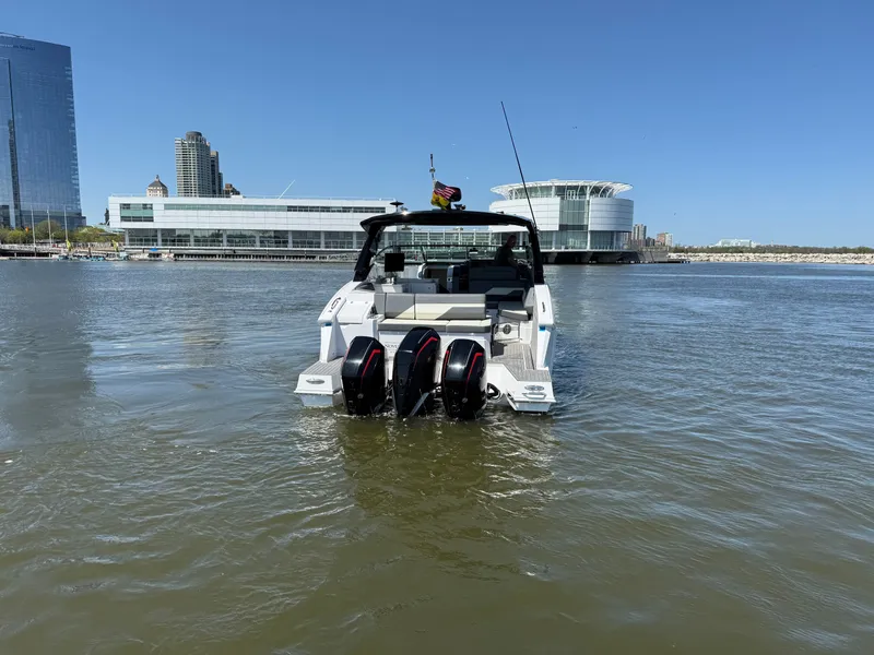 Slide: The Image of 2021 Cruisers Yachts 38 GLS on water with modern architecture backdrop. - 8