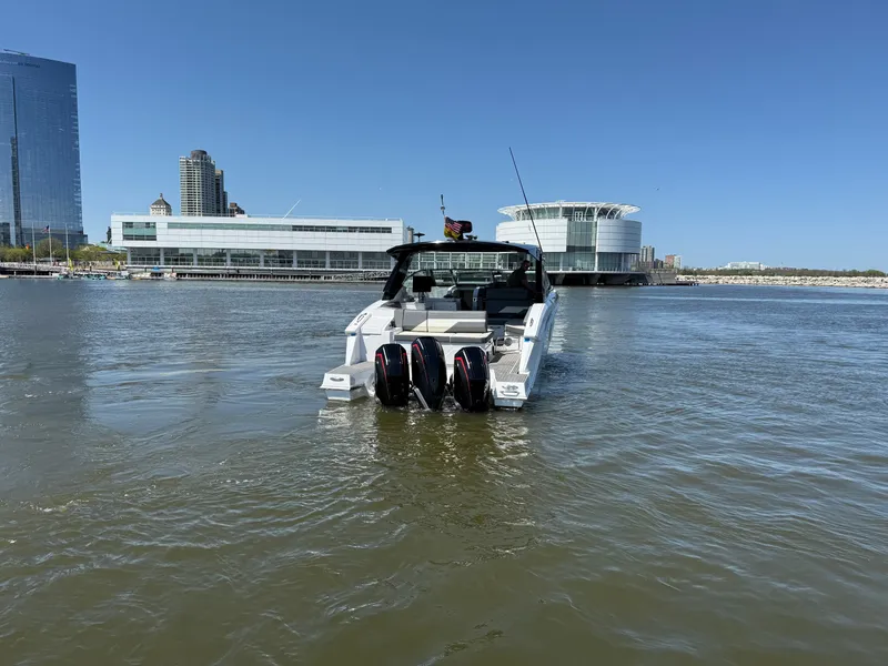 Slide: The Image of 2021 Cruisers Yachts 38 GLS on water with modern architecture backdrop. - 9