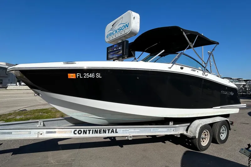 The Image of 2018 Cobalt 25SC boat on trailer, black hull, sunny day, Erickson Marine sign. - 1