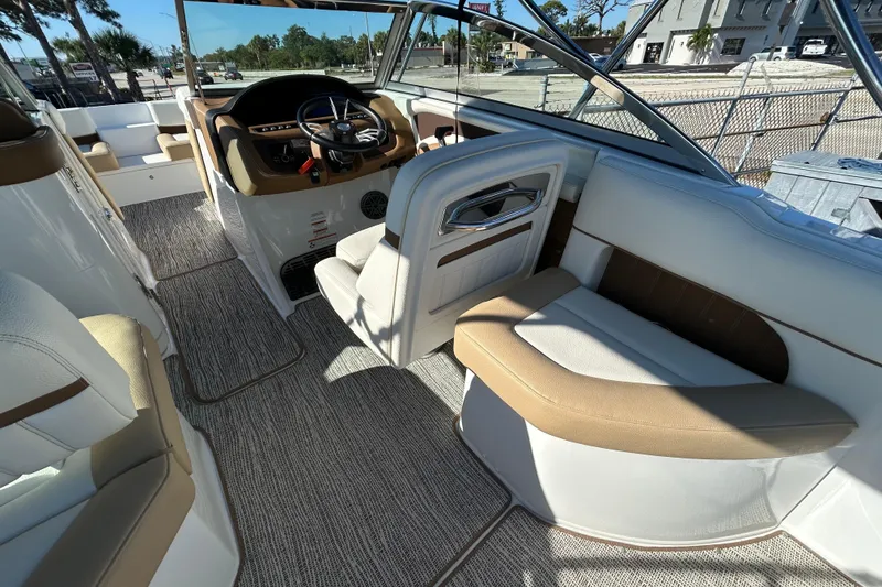 Slide: The Image of 2018 Cobalt 25SC boat interior with beige and white seating, steering wheel, and carpeted flooring. - 17