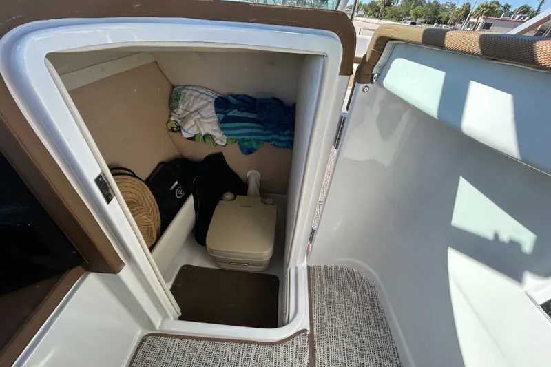 Slide: The Image of 2018 Cobalt 25SC boat interior with storage compartment and portable toilet. - 23