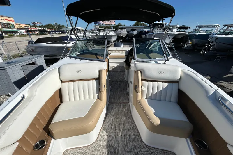 Slide: The Image of 2018 Cobalt 25SC boat interior with beige and white seating, docked among other boats. - 25