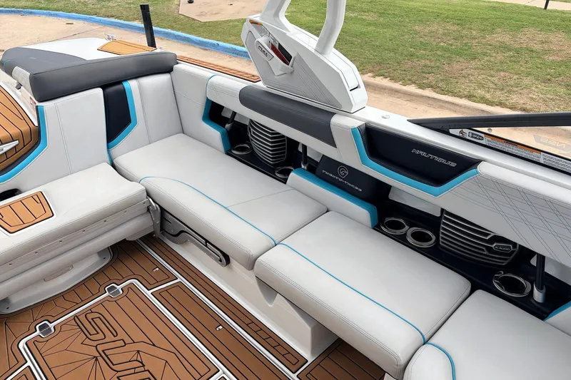 Slide: The Image of 2017 Nautique Super Air Nautique G23 interior with white and blue seating, cup holders, and teak flooring. - 21