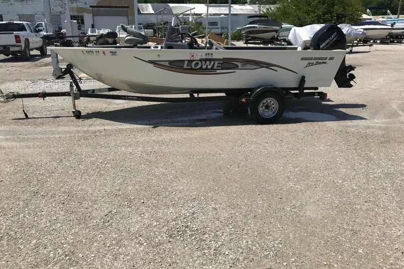 The Image of 2014 Lowe Fishing Machine 165SC Pro boat on trailer in a parking lot. - 1