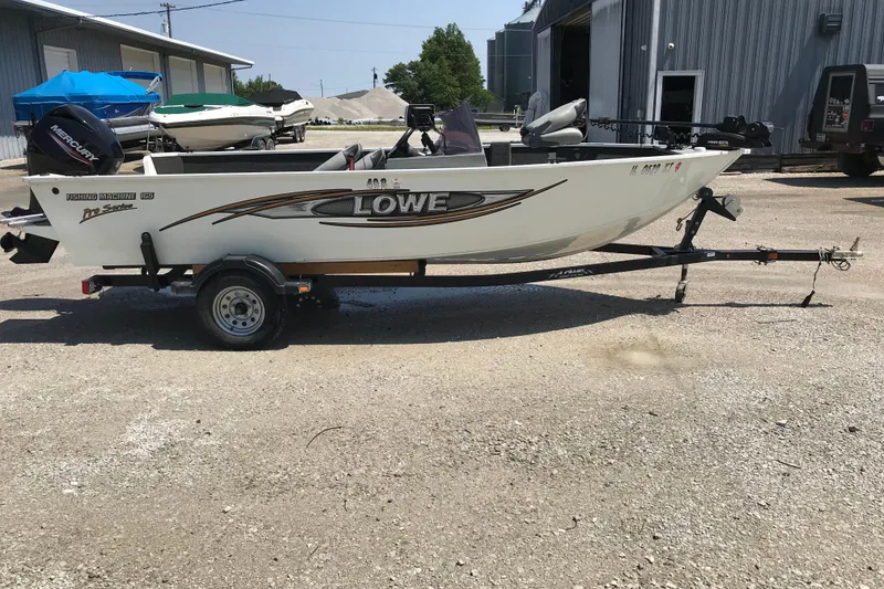 Slide: The Image of 2014 Lowe Fishing Machine 165SC Pro boat on trailer, parked outdoors. - 2