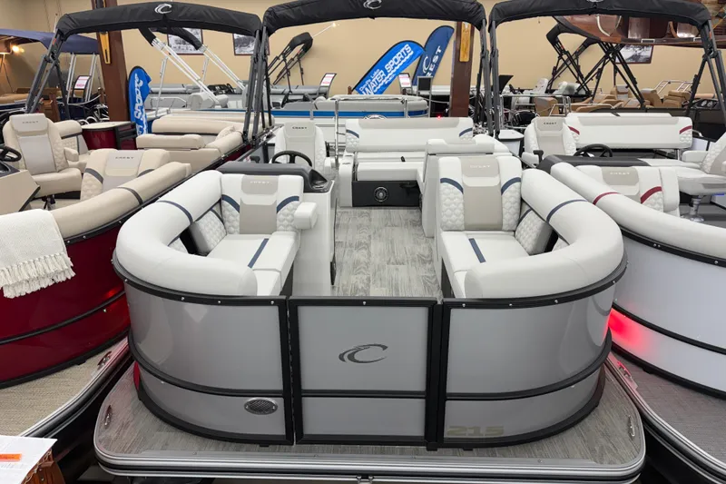 Slide: The Image of 2026 Crest Conquest 210 SLS pontoon boat with luxurious seating and modern design in showroom. - 1
