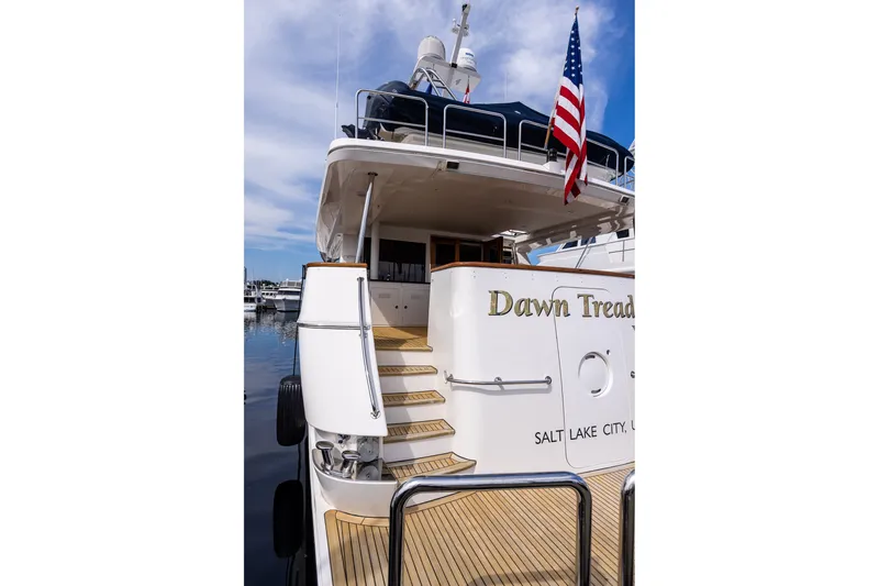 Slide: The Image of 2005 West Bay 86 Raised Pilothouse Motor Yacht docked, featuring elegant design and American flag. - 146