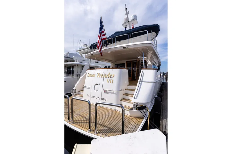 Slide: The Image of 2005 West Bay 86 Raised Pilothouse Motor Yacht docked, featuring elegant design and American flag. - 147