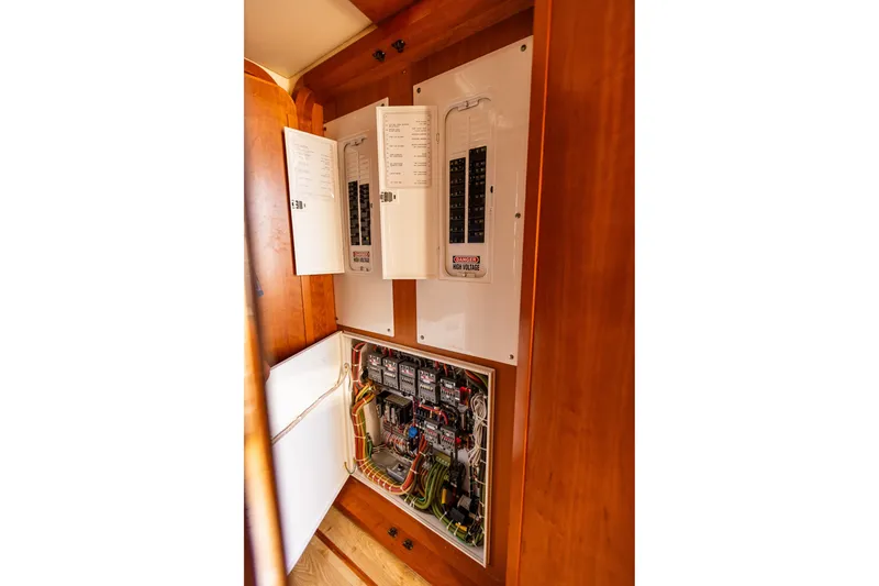 Slide: The Image of Electrical panel inside 2005 West Bay 86 Raised Pilothouse Motor Yacht, showcasing wiring and circuit breakers. - 113