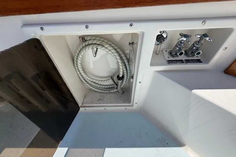 Slide: The Image of Compartment with coiled hose and faucets on a 1985 Formula 31 Performance Cruiser. - 3