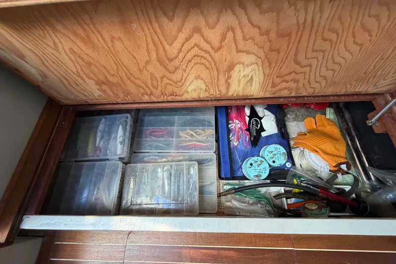Slide: The Image of Storage compartment in a 1985 Formula 31 Performance Cruiser with fishing gear and tools. - 61