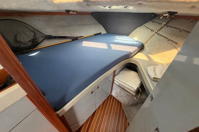Slide: The Image of 1985 Formula 31 Performance Cruiser cabin with blue mattress and wooden accents. - 64