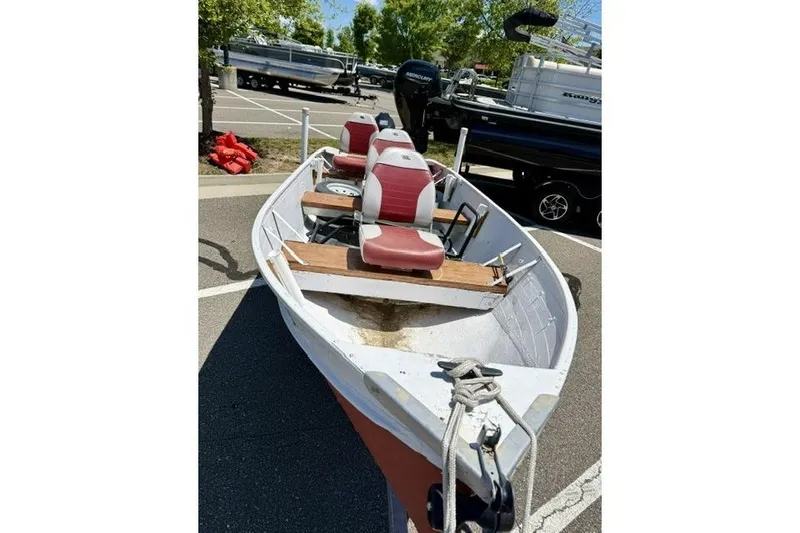 Slide: The Image of 1958 Jon Boat Aluminum model with red seats, parked in a lot under sunny skies. - 3