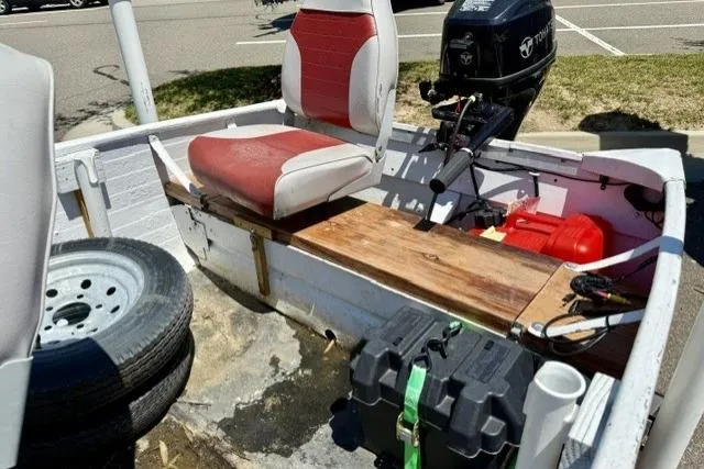 Slide: The Image of 1958 Jon Boat Aluminum with red seats, outboard motor, and spare tire in parking lot. - 7
