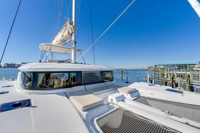 Slide: The Image of 2022 Lagoon 46 catamaran docked, featuring spacious deck and modern design against clear blue sky. - 11
