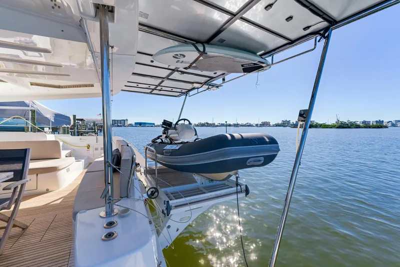 Slide: The Image of Lagoon 46 catamaran, 2022 model, with a tender on the deck, overlooking a serene waterfront. - 12