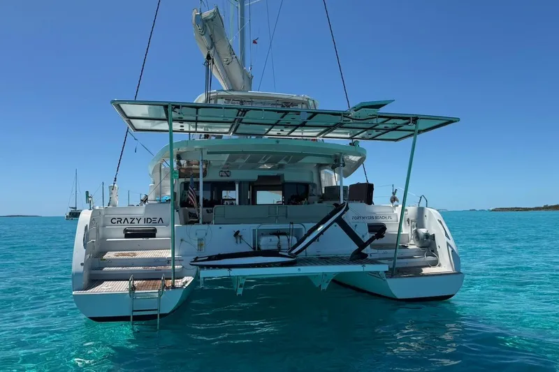 Slide: The Image of 2022 Lagoon 46 catamaran on clear blue water, rear view with open deck. - 3