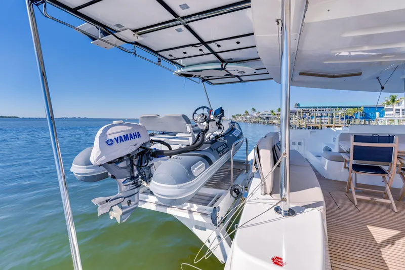 Slide: The Image of 2022 Lagoon 46 yacht with Yamaha motorboat on deck, docked by calm waters. - 7