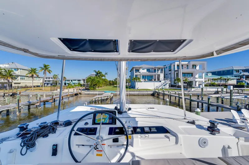 Slide: The Image of Cockpit view of 2022 Lagoon 46 catamaran docked at a marina with waterfront homes. - 9
