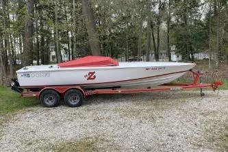 The Image of 1996 Donzi 22 Classic boat on trailer, parked outdoors with red cover. - 0