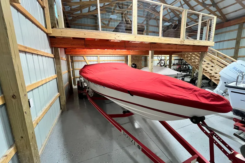 The Image of 1996 Donzi 22 Classic boat with red cover in a wooden storage shed. - 1