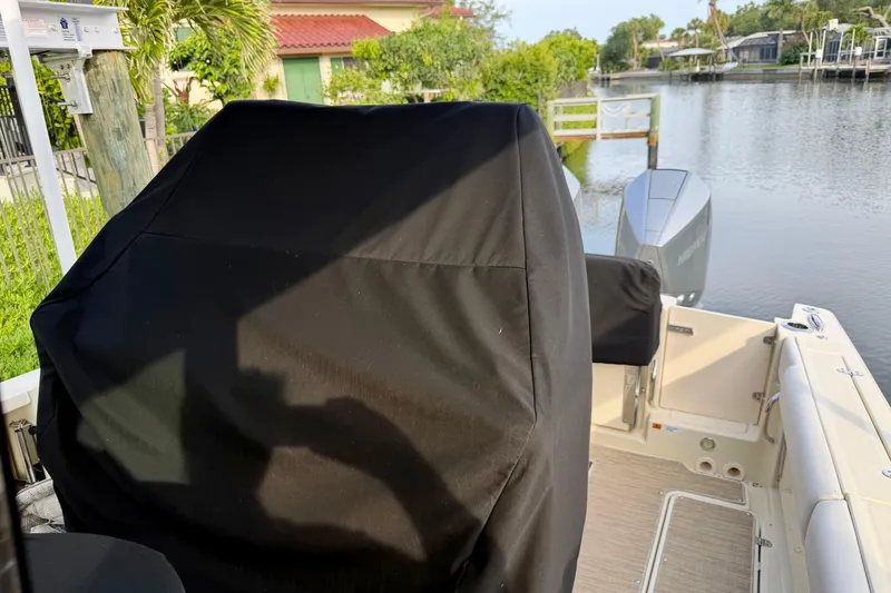 Slide: The Image of 2024 Chris-Craft Catalina 30 boat with covered seating, docked by a serene waterfront. - 19