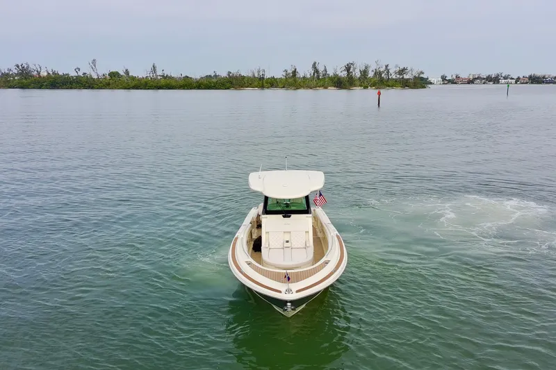 Slide: The Image of 2024 Chris-Craft Catalina 30 boat cruising on calm waters near a lush shoreline. - 36