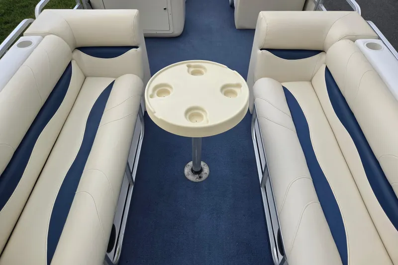 Slide: The Image of 2004 Odyssey Pontoons 2302 Millennium interior with cream and blue seating, round table, and cup holders. - 10