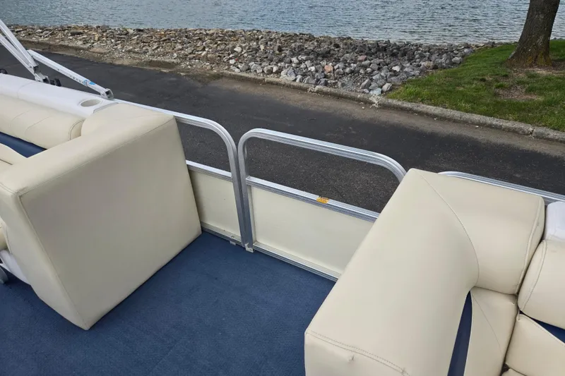 Slide: The Image of 2004 Odyssey Pontoons 2302 Millennium interior with beige seating and blue carpet by the water. - 12
