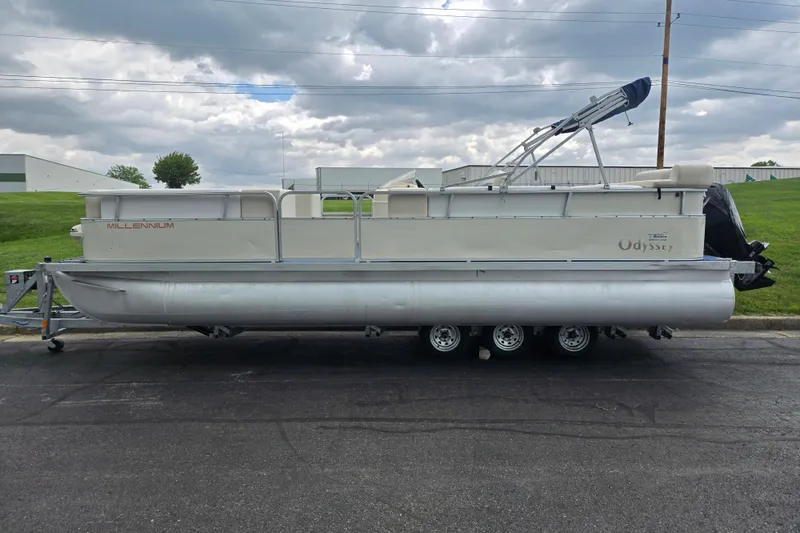 Slide: The Image of 2004 Odyssey Pontoons 2302 Millennium pontoon boat on trailer, parked outdoors under cloudy sky. - 4