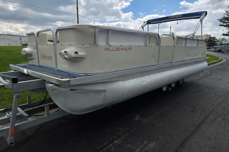 Slide: The Image of 2004 Odyssey Pontoons 2302 Millennium on trailer, parked outdoors under cloudy sky. - 5