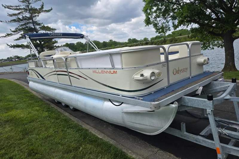 Slide: The Image of 2004 Odyssey Pontoons 2302 Millennium on trailer by a lakeside, under cloudy sky. - 8