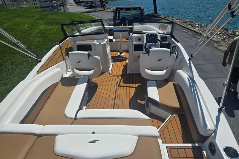 Slide: The Image of 2023 Starcraft SVX 230 IO boat interior with tan and white seating, docked by a lake. - 10