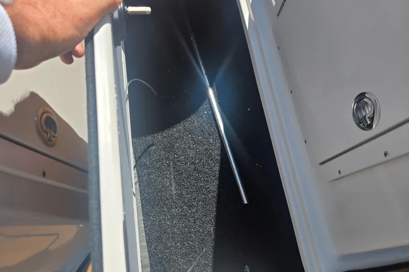Slide: The Image of Storage compartment in 2023 Starcraft SVX 230 IO boat, featuring carpeted interior and metal rod. - 16