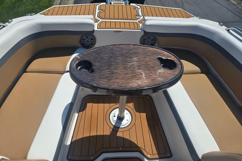 Slide: The Image of 2023 Starcraft SVX 230 IO boat interior with wood table and cushioned seating. - 18