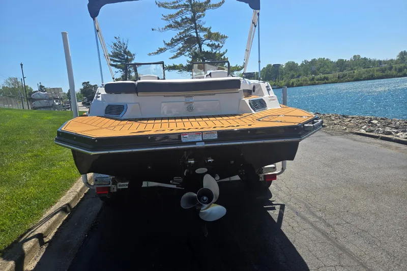 Slide: The Image of 2023 Starcraft SVX 230 IO boat docked by a scenic waterfront. - 2