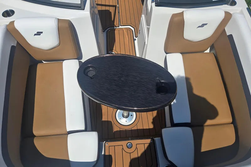 Slide: The Image of 2023 Starcraft SVX 230 IO boat interior with tan and white seating, and a central table. - 20